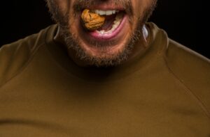 man biting into walnut